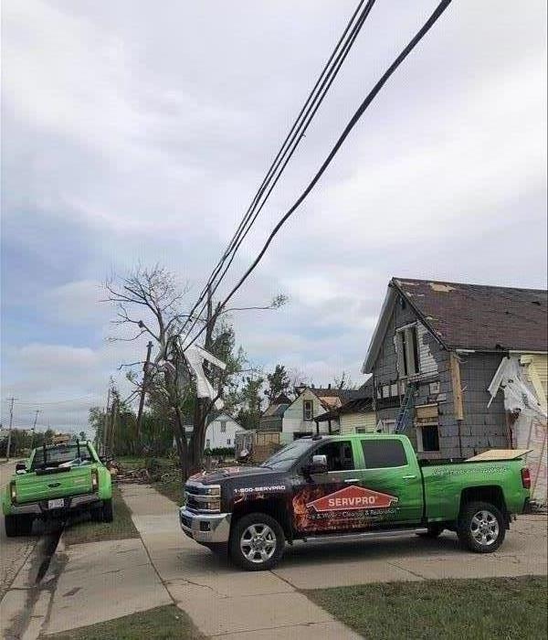 Pictured are destroyed houses and two SERVPRO vehicles in the front.